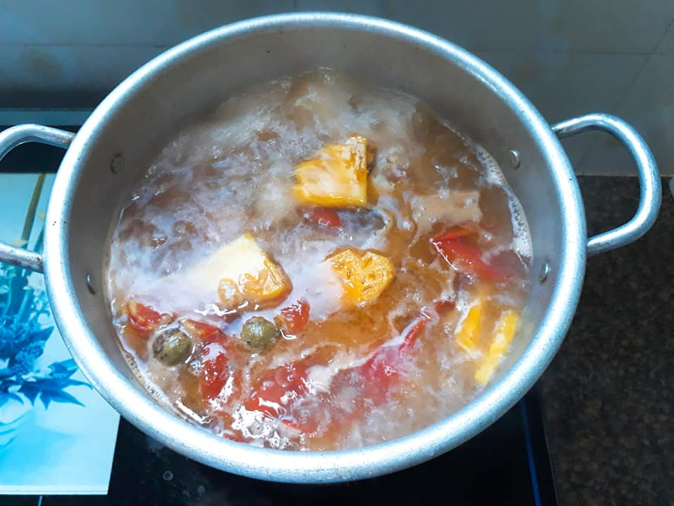 Nồi canh chua đầu cá đang sôi với dứa và cà chua